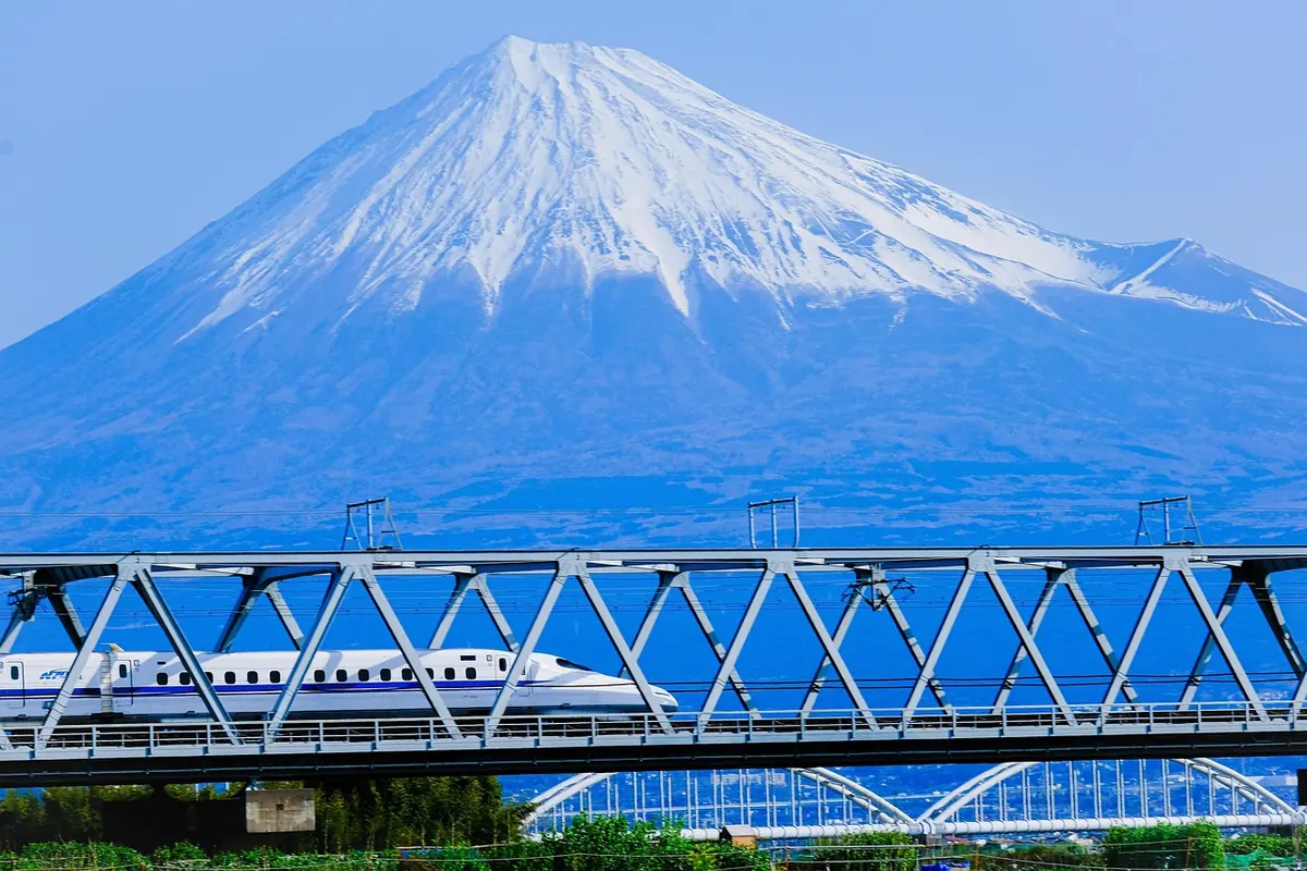 A shinkansen crossing a bridge with Mount Fuji behind